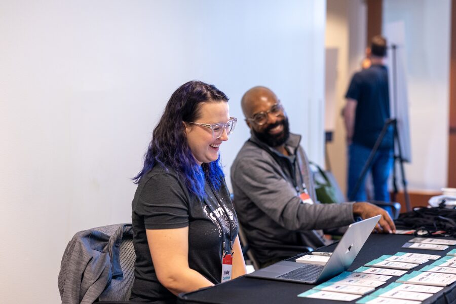 two people sitting at a registration table smiling